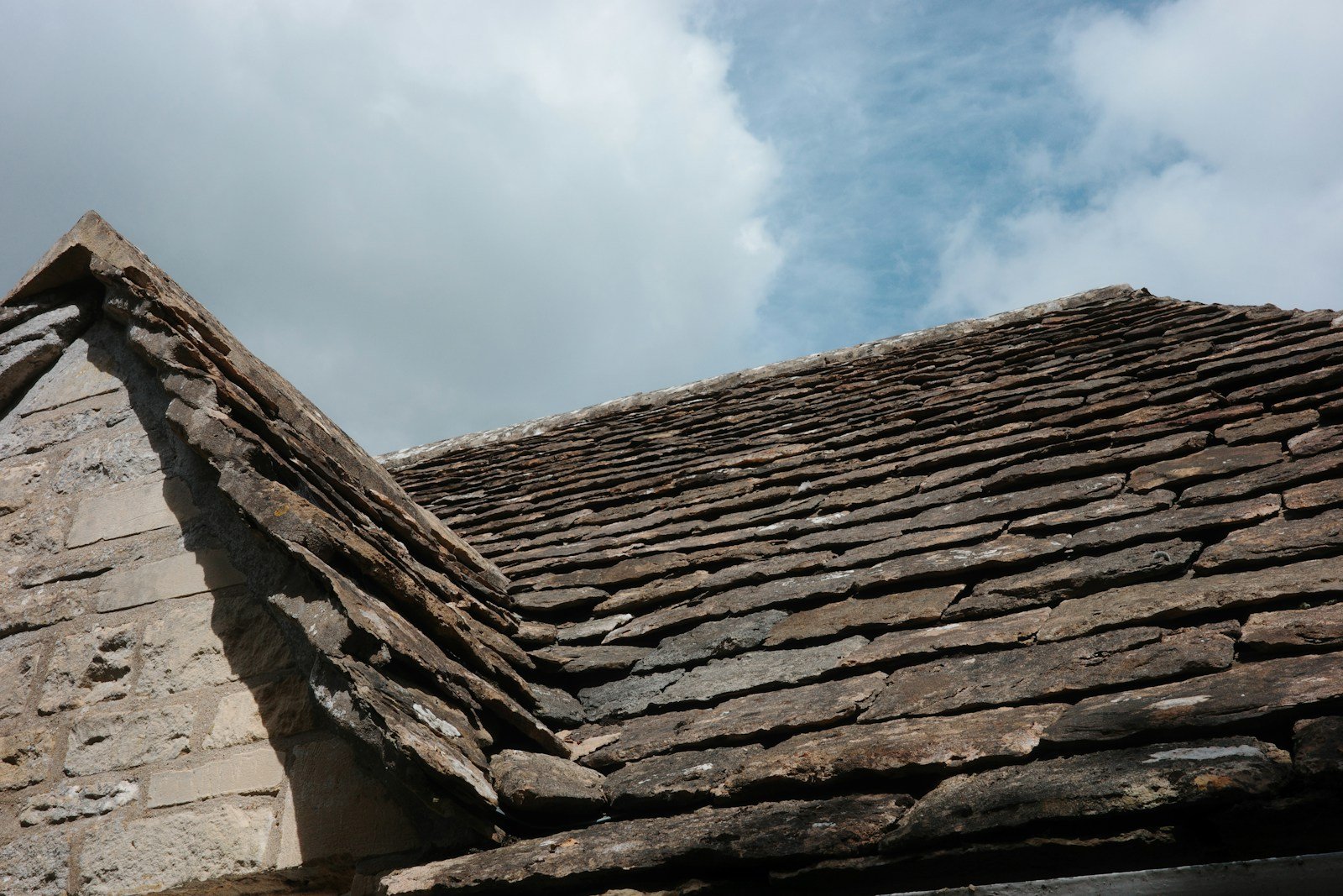 Jonction entre un mur en pierre calcaire et une couverture en tuiles