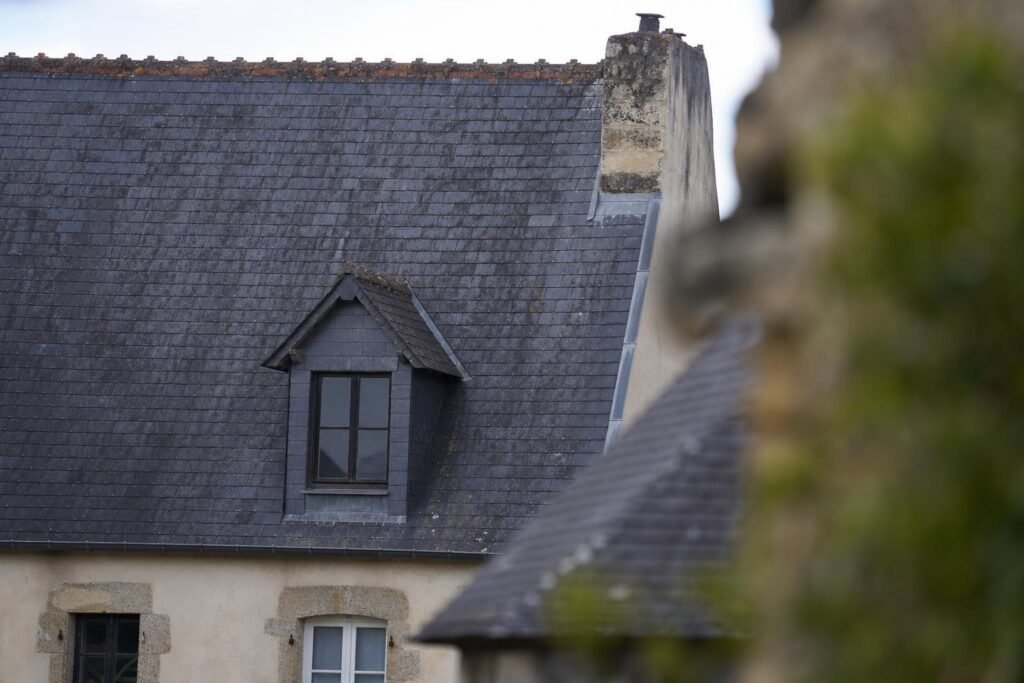 Toiture en ardoise naturelle d'une maison ancienne, ardoises sombres aux teintes légèrement inégales